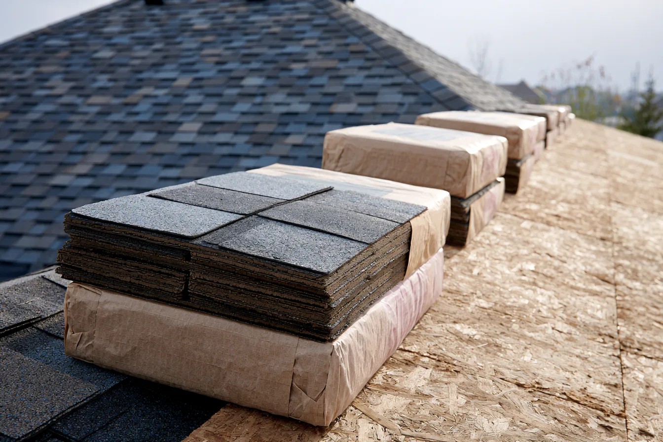 Wrapped asphalt shingle bundles staged on exposed roof decking